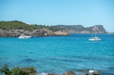 Cala Nova, Ibiza: 2024 May 12: Panorama on the tourist beach of Cala Nova on the island of Ibiza in summer 2024. clipart