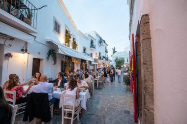 İbiza, İspanya: 16 Mayıs 2024: 2024 yazında insanlar İbiza 'nın eski turizm kasabası Dalt Vila sokaklarında yemek yiyor.