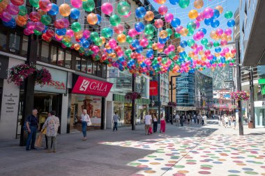 Andorra La Vella, Andorra: 15 Temmuz 2024: İnsanlar Meritxell adı verilen alışveriş caddesi boyunca yürüyorlar. Başkent Andorra la Vella, Andorra 'da 2024 yılında renkli toplarla süslenmişler..