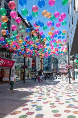 Andorra La Vella, Andorra: 15 Temmuz 2024: İnsanlar Meritxell adı verilen alışveriş caddesi boyunca yürüyorlar. Başkent Andorra la Vella, Andorra 'da 2024 yılında renkli toplarla süslenmişler..
