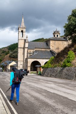 Pilgrim passing by the Hermitage of Our Lady of Angustias in Molinaseca in Leon, on the Camino de Santiago. clipart