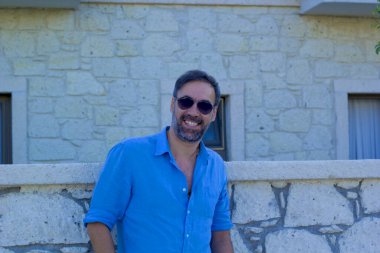 Kameraya gülümseyen güneş gözlüklü yakışıklı bir adam portresi.