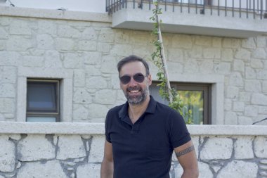 Kameraya gülümseyen güneş gözlüklü yakışıklı bir adam portresi.