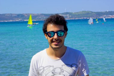 Sahilde güneş gözlüklü genç bir adamın portresi.