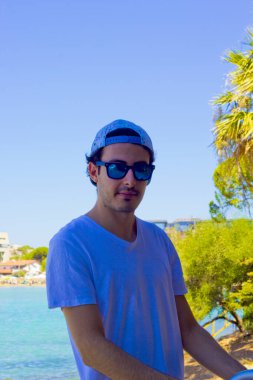 Güneş gözlüklü çocuk plajda spor yapıyor.