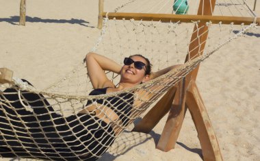 Güneş gözlüklü güzel bir kadın Giftun Adası sahilinde dinleniyor.