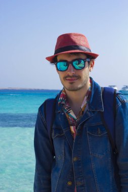 Güneş gözlüklü genç bir adamın portresi ve Hurgada 'da kırmızı şapka, kızıl deniz Mısırı