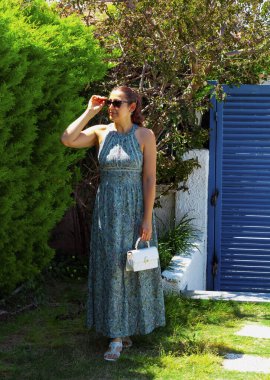 Bahçede güneş gözlüklü güzel bir genç kadının portresi.