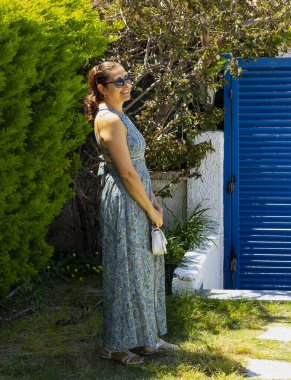 Bahçede güneş gözlüklü güzel bir genç kadının portresi.