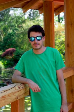 Güneş gözlüklü genç bir adamın, kameraya bakarken portresi.