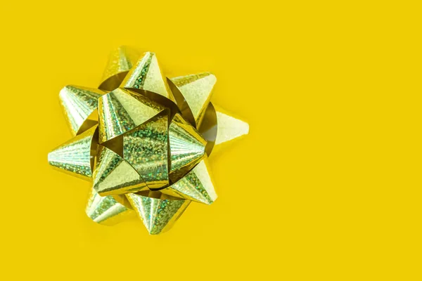Happy New Year. Holiday banner Merry Christmas. Gold bow sparkling holiday gift on a yellow background.