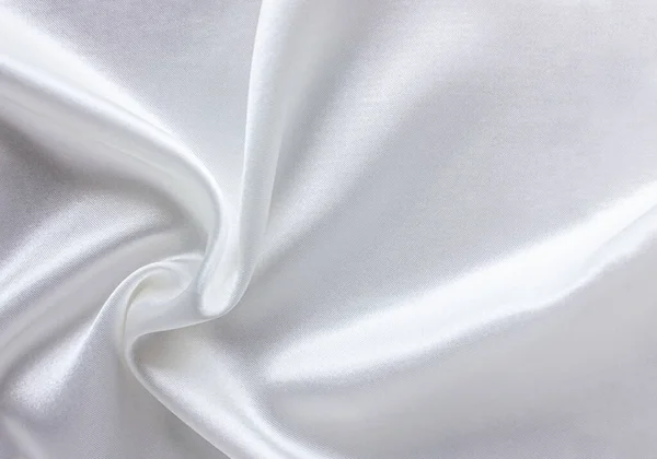 White satin fabric as background. Closeup of rippled white silk fabric with copy space. Satin luxury cloth texture can use as wedding background.