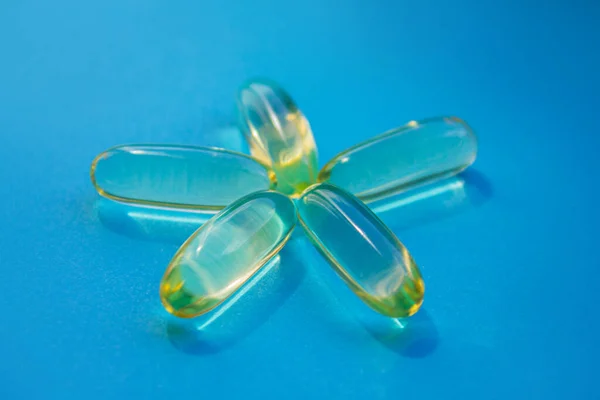 Vitamin E capsules in the form of the sun. Vitamin D, Fish oil, Omega, Omega-3 on a blue background. Health promotion, healthy lifestyle, medicine, cosmetology, diet, mental health