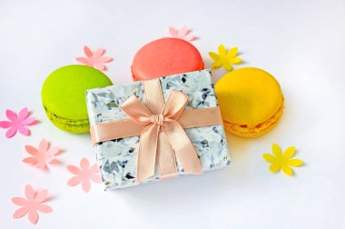 Kağıt çiçeklerle donatılmış hafif bir zemin üzerinde hediye kutusu ve makarna..