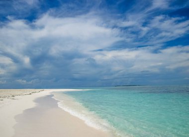Muhteşem kumlu kumsal mavi turkuaz suya harika bir manzara. Okyanus ve mavi gökyüzüyle plajda güneşli bir gün..
