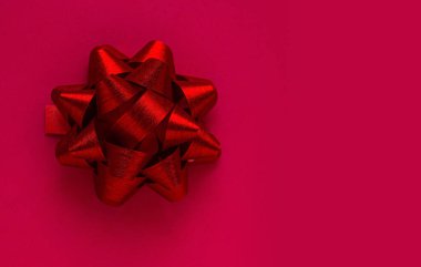 Parlak kırmızı arka planda kırmızı hediye yayı. Noel ya da Sevgililer Günü için kırmızı arka planda kırmızı hediye afişi.