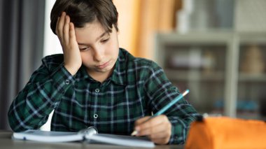 Sıkılmış çocuk ödevini yapıyor.