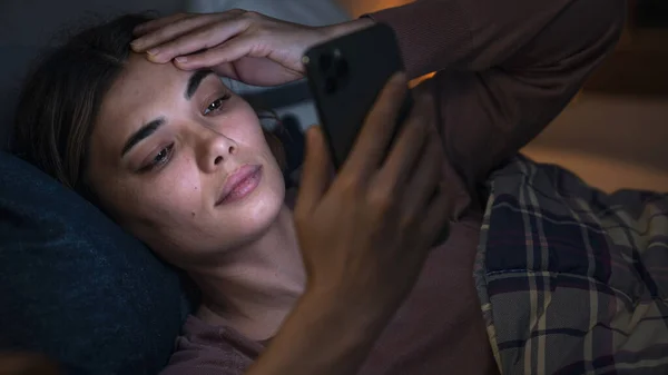 夜间躺在床上用手机的妇女 — 图库照片