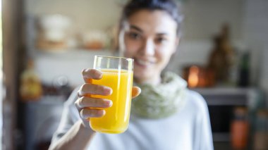 Genç bir kadın portakal suyu içiyor.