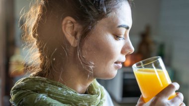 Genç bir kadın portakal suyu içiyor.