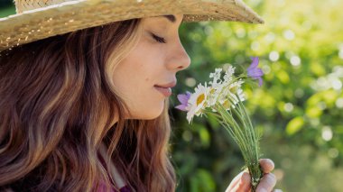 Elinde kır çiçekleri olan genç bir kadın.