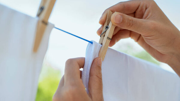 Женские руки вешают белье на веревку