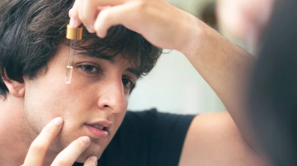 stock image Young man dripping serum on his face