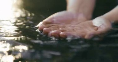 A female hand touching the river water