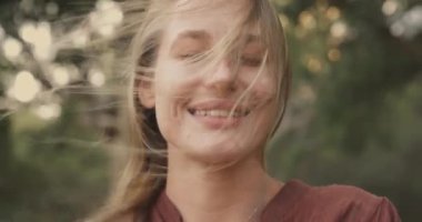 Rüzgar, gözleri kapalı bir kadının saçlarını savuruyor.