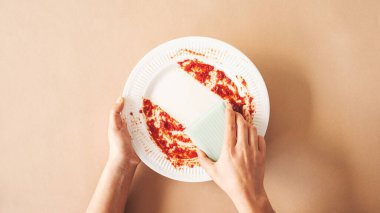 Yemek yedikten sonra yemek lekelerini ve kiri temizlemek için yeşil temizlik süngeri kullanan kadın.