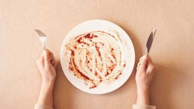 Açlık konsepti. Boş tabağı tutan kadın yemek bekliyor. Üst görünüm