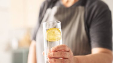 Bir bardak su, elinde limon dilimi olan kadın.
