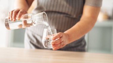 Bir bardak içme suyu tutan kadın.