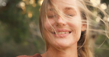 Rüzgar, gözleri kapalı bir kadının saçlarını savuruyor.