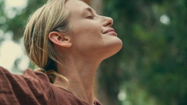 Kadın kollarını kaldırıyor ve doğayı kucaklıyor.