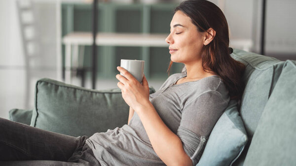 Молодая женщина пьет кофе дома