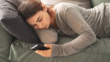 Genç bir kadın tüm zamanını cep telefonuyla geçirir.