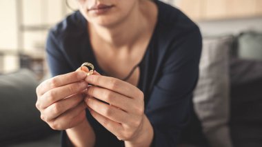 Kadın alyansını çıkarıyor.