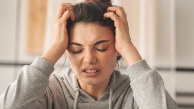 Genç bir kadın parmaklarıyla kafa derisini ve saçlarını kaşıyor. Saç sağlığı konsepti