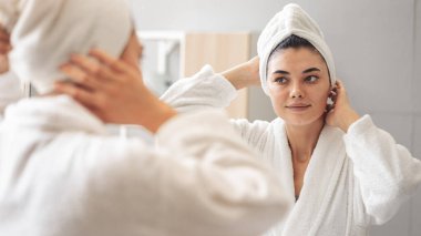 Aynadaki yansıma güzel bir kadın kozmetik cilt bakımı yapıyor.