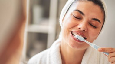 Genç bir kadın dişlerini fırçalıyor.