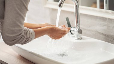 Banyoda ellerini yıkayan bir kadın.