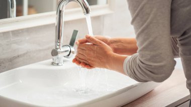 Banyoda ellerini yıkayan bir kadın.