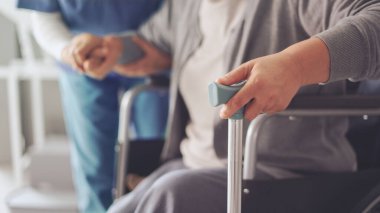Hemşire yaşlı hastaya bastonla yardım ediyor.