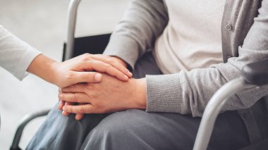 Genç bakıcı yardımcı eller için yaşlı kadın veriyor