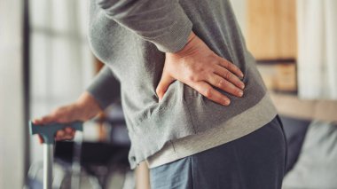 Evde bastonu olan yaşlı bir kadın.