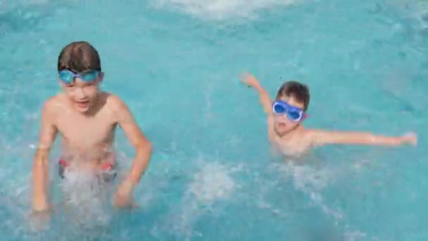 陽気な子供たちは 水の子供たちが楽しい夏休みを泳いでプールを泳ぐ 幸せな子供たちプール楽しいスプラッシュ水幸せな夏の子供たちプールで水しぶき子供の休日の夏の旅行楽しい男の子 — ストック動画