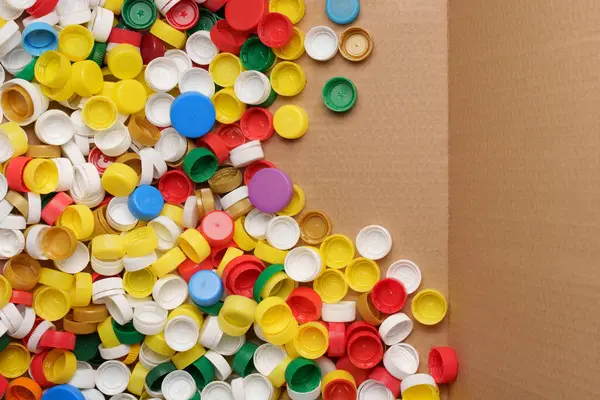 Colorful bottle caps background cardboard box. Used PET recycling plastic bottle cap plastic lids. Garbage PET waste recycling bottle cap sorting waste plastic garbage collection. Recyclable materials
