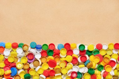 Karton arka planda plastik kapak koleksiyonu. PET geri dönüşüm plastik şişe kapağı geri dönüşüm kapağı geri dönüşüm arka planında PET plastik kapaklar. Geri dönüşümlü malzemeler. Atık ayrıştırması sınıflandırılıyor.