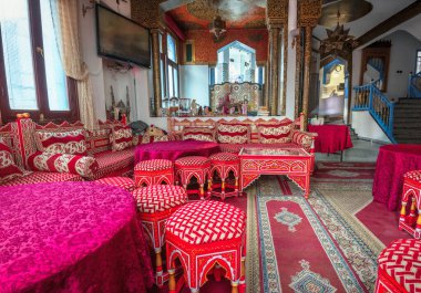 CHEFCHAOUEN, MOROCCO - 02 Temmuz 2018: Renkli Arap tarzıyla geleneksel süslenmiş otel odasının içi. Mobilyalar, yastıklar ve halılar tipik deco ile